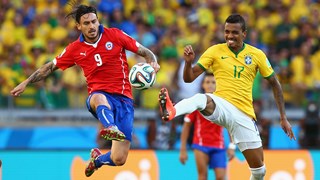 Mauricio Pinilla of Chile and Luiz Gustavo of Brazil compete for the ball
