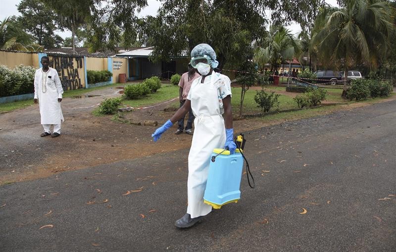 Enfermeira passa desinfetante nas imediações de hospital usado para tratar pacientes com ebola, na Libéria (Foto: EFE)