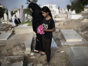 Mulher palestina e menina levam flores em um túmulo da família no feriado do fim do Ramadã (Eid al-Fitr) em Gaza.  (Foto: Reuters/Finbarr O'Reilly)