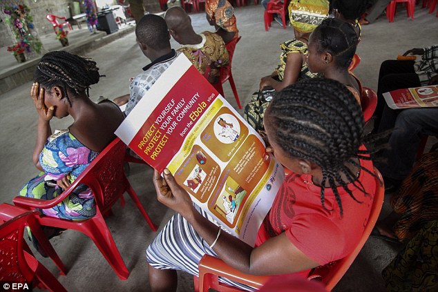 Aviso de Orientação: Uma mulher lê um cartaz liberiano informações sobre a prevenção da epidemia de Ebola