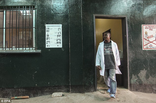 Resposta Médico: Uma enfermeira liberiano passa por um cartaz ilustrando passos para enfermeiros para colocar em roupas de proteção exibido na Redenção Hospital onde uma enfermeira teria morrido do vírus Ebola em Monrovia