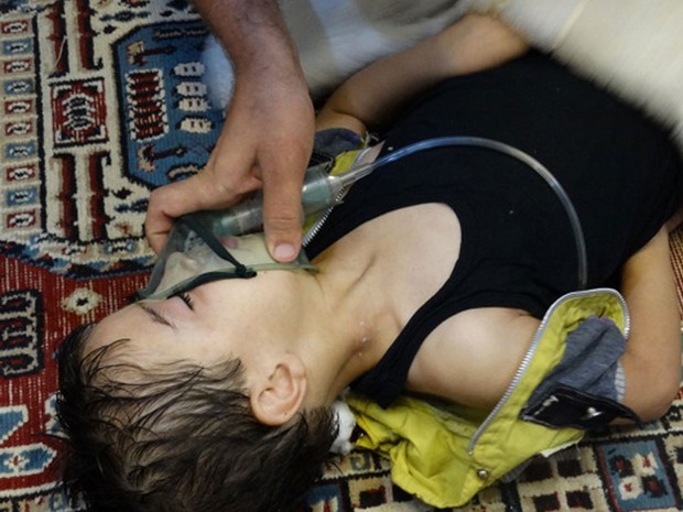 21/8 - Menino recebe cuidados e respira com a ajuda de uma máscara de oxigênio em Damasco após ataque de forças do governo (Foto: Maher al-Zaybaq/Shaam News Network/Reuters)